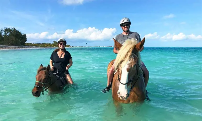 horseback riding in providenciales on long bay beach two riders on horses in ocean