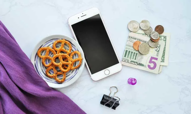 importance of saving money items laying on counter money phone pretzels