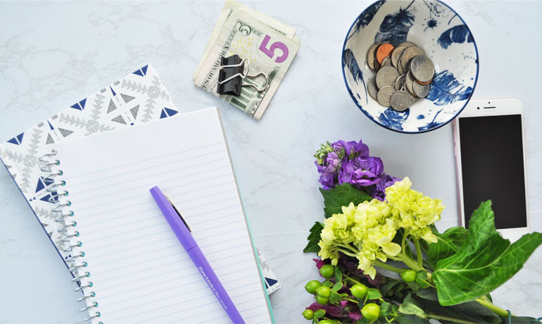 is saving money important money lyiing on desk with flowers and phone