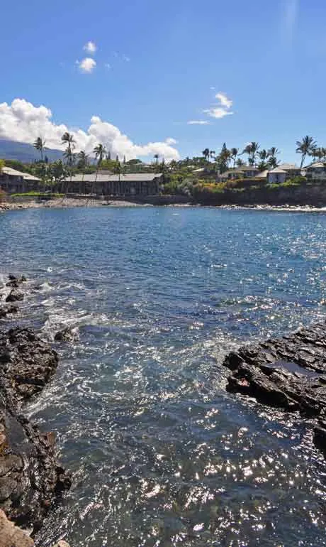 ocean water with rocky shore and condos in the background