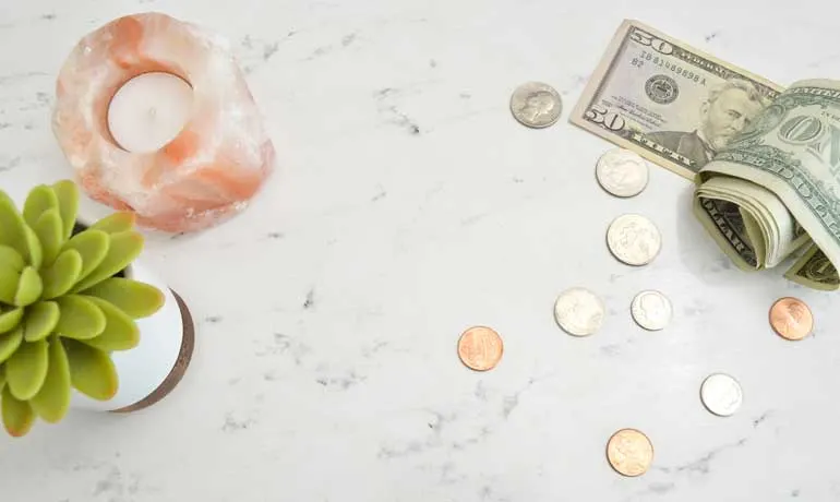why saving money is important money on countertop with candle and succulent