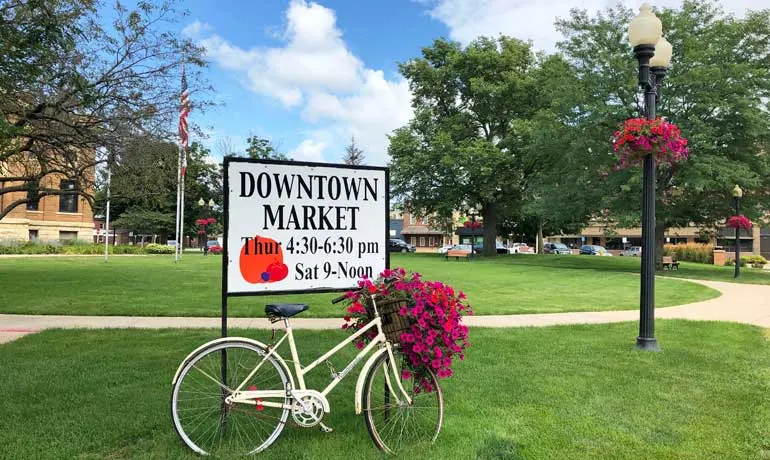 downtown market estherville sign with bike and town square with flowers