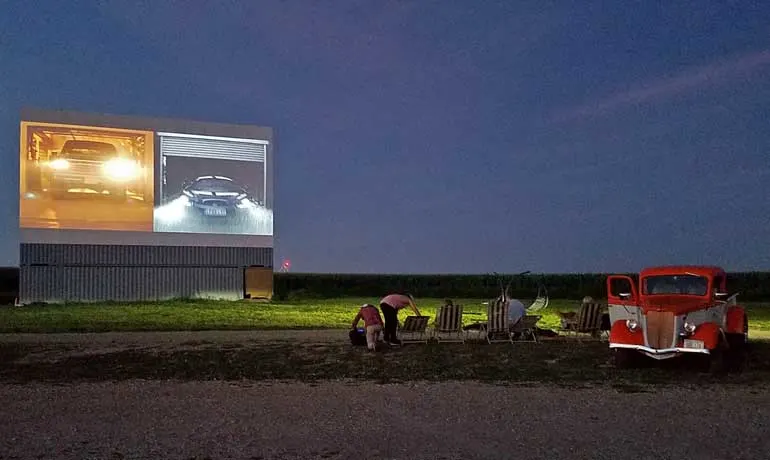 old fashioned drive in movie with classic car and screen