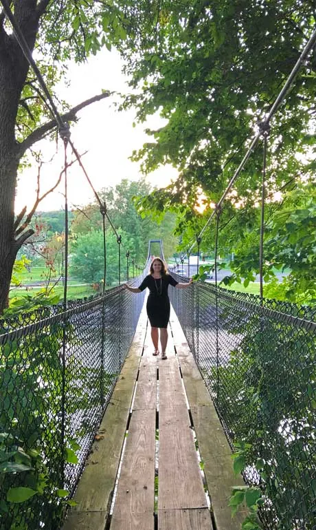 wooden swinging bridge - shesavesshetravels nikki standing on bridge