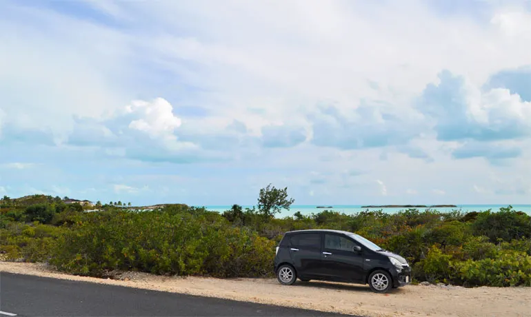 rent a car in turks and caicos car along the road with beach in background