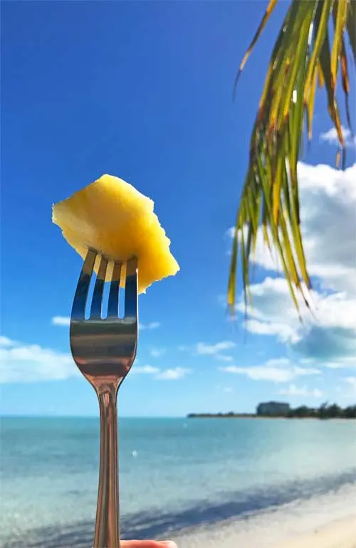 eating for cheap in the caribbean - pineapple on fork at the beach