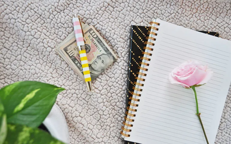 money with notebook and rose
