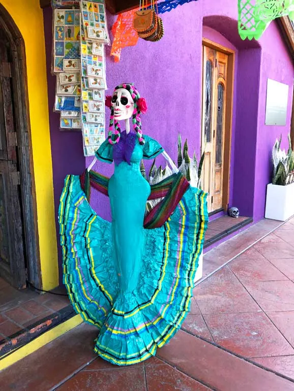 colorful Dia de los Muertos mannequin with buildings