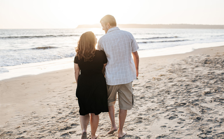 couple on beach looking at each other at sunset