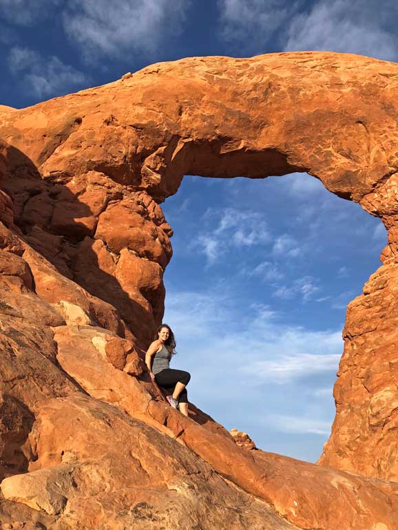arches national park in April woman sitting inside arch