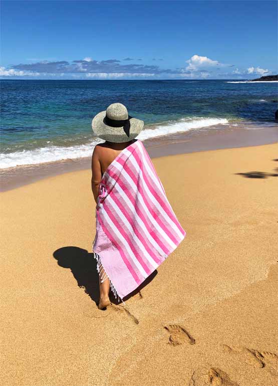 pink beach towel with woman standing on beach