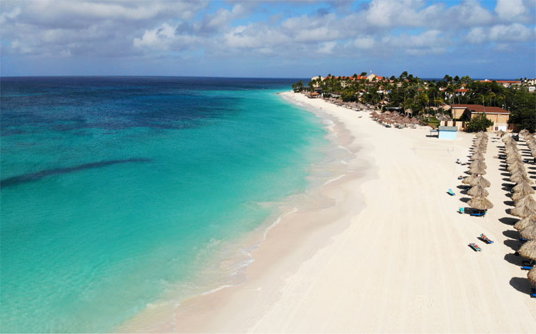 caribbean getaways aruba beach with teal water white sand and huts