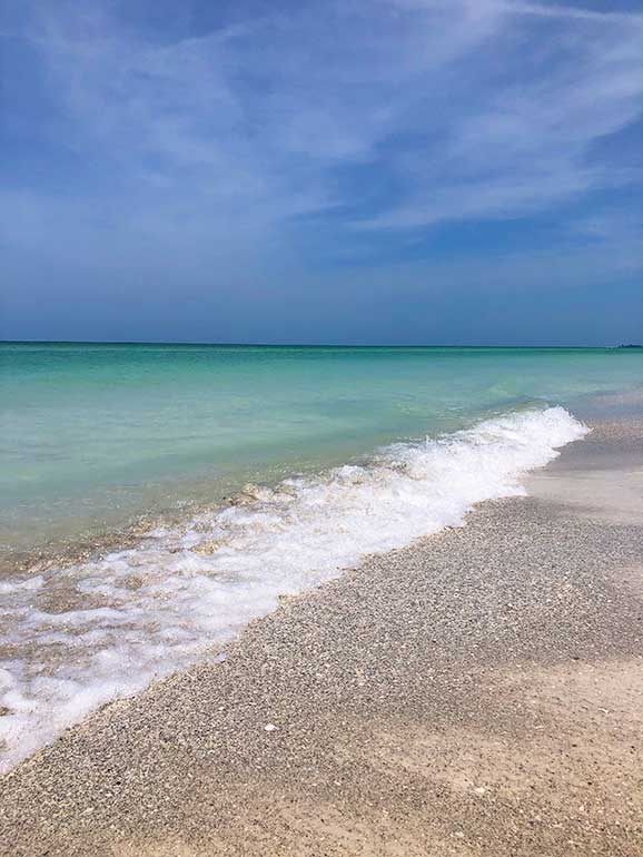 best kid beaches in florida sandy beach white waves teal water blue sky