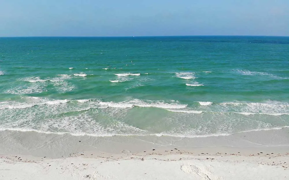 family beaches in florida aerial view of white sand beach teal water and white cap waves