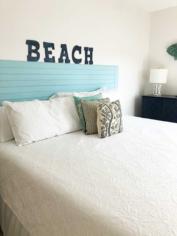 photo of white bed with pillows and the word beach above it