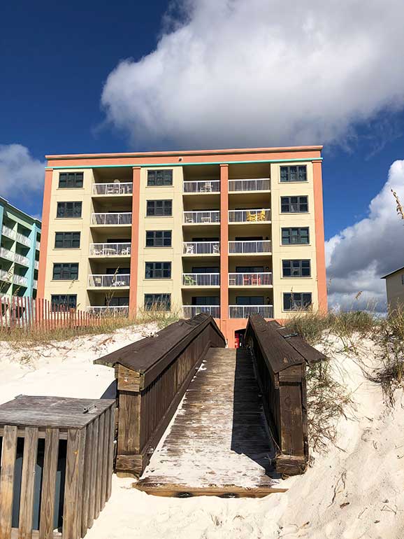 condo building with orange and a walkway to it on the sand