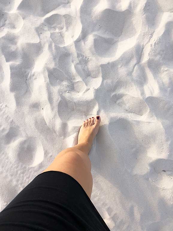 bright white sand as woman's foot steps on it