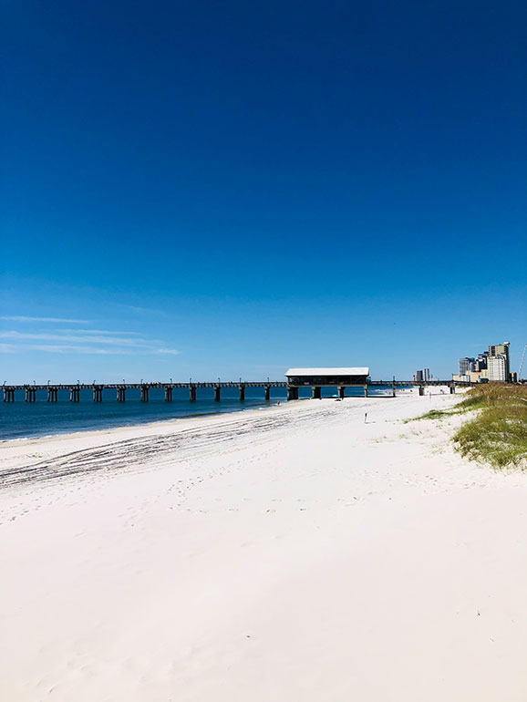 photo of blue sky, pier and white sand