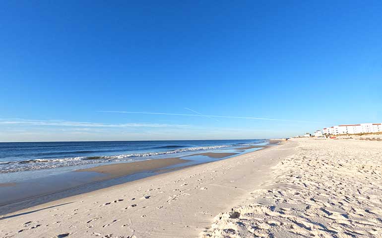 Orange Beach Alabama beach with white sand and blue sky, gentle waves