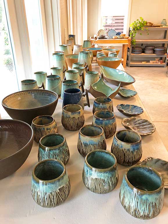 pottery lined up on a table cups bowls and mugs