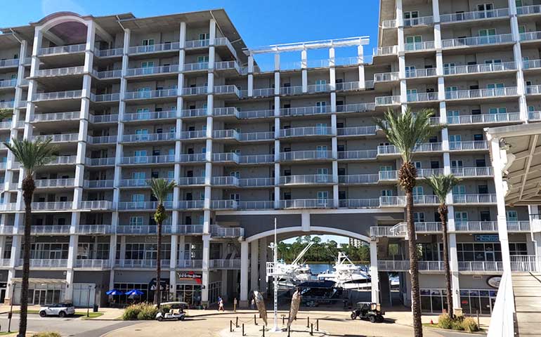 the wharf orange beach condos front of building with palm trees and fish sculpture