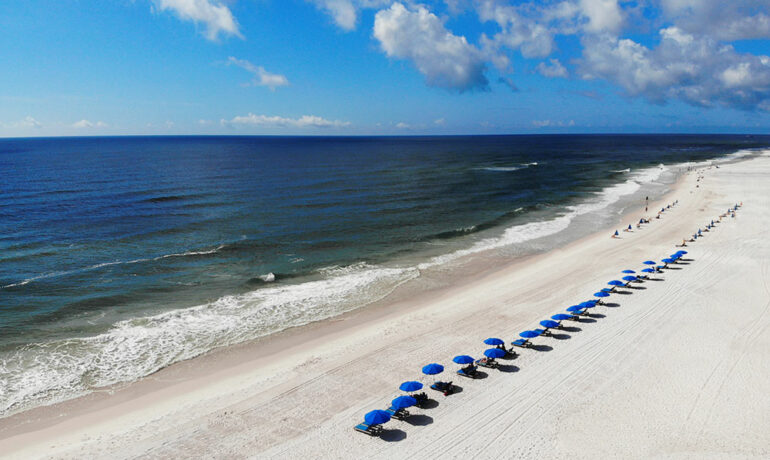 things to do in orange beach alabama photo of sitting on the white beach with blue water and beach umbrellas from above