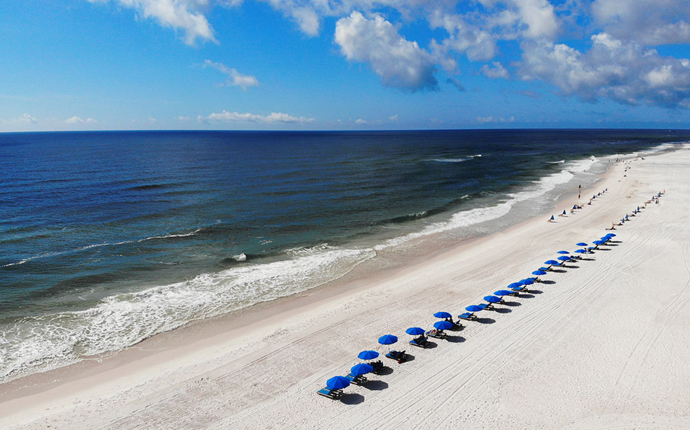 visit the beaches of Alabama white sand blue water umbrellas