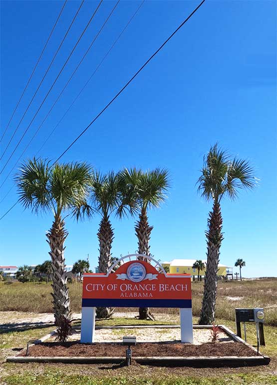Orange Beach Alabama welcome sign with palm trees in background