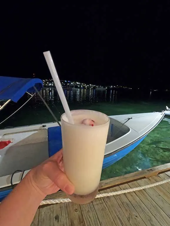 pina colada with boat and pier in background at night