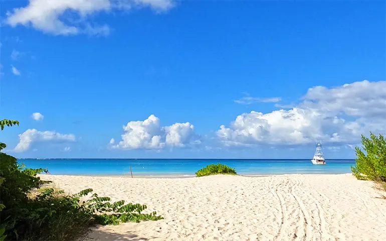 turquoise ocean with sandy shore and boat on a sunny day