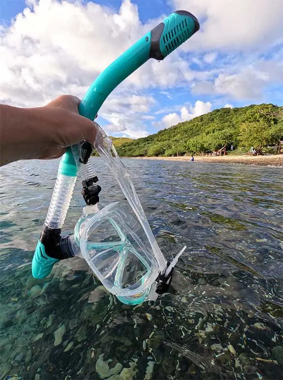 packing for culebra pr woman holding snorkel set with beach in background