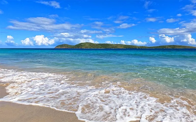 zoni beach pr white waves, teal water and island in distance