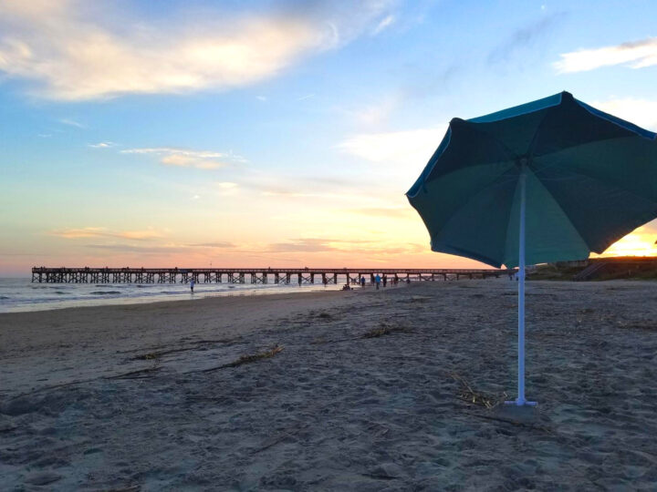best honeymoon spots in the US beach at sunset with umbrella and pier