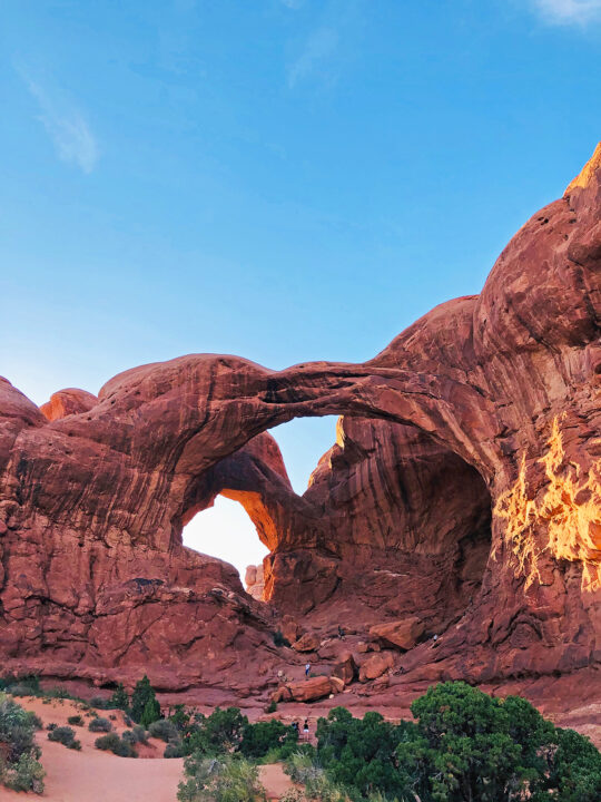 best honeymoon destinations for active people hiking through large arch out of sone with trees in foreground