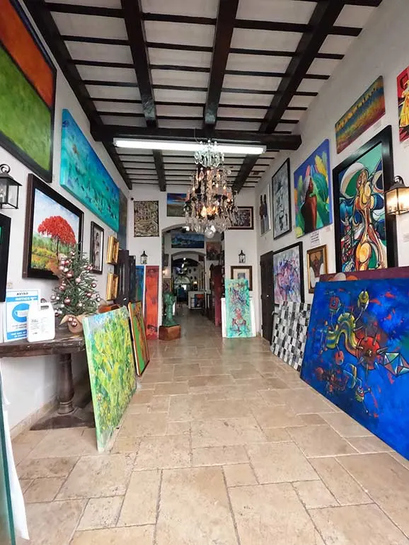 view into art gallery in old San Juan paintings all around the walls with tile floor and decorative ceiling