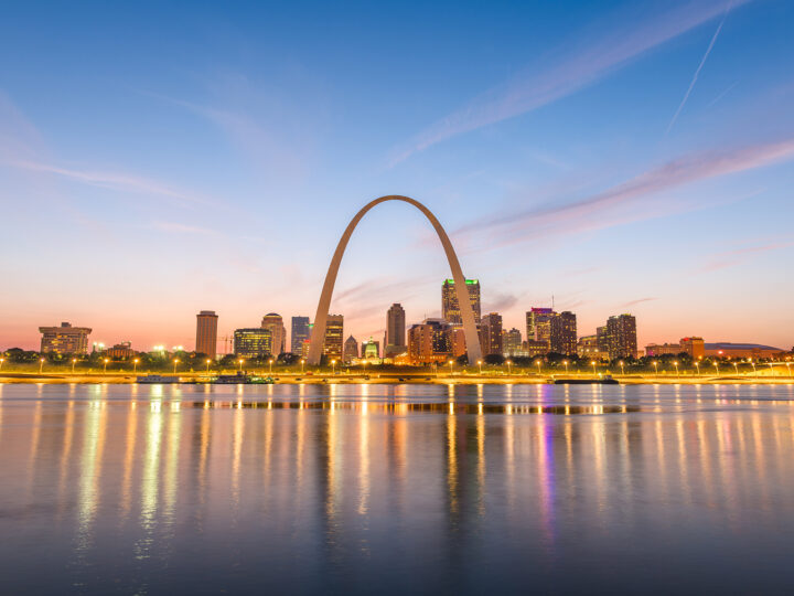 st louis arch at dusk on a colorful sunset with water in the foreground