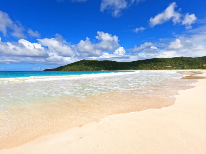 Puerto Rico beach with waves, blue water and hillside in background