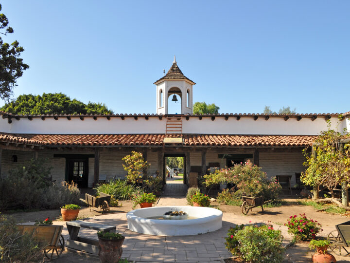 old Spanish architecture building with bell tower, courtyard and flowers