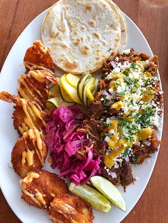 plate of food including fried shrimp, meat with pico, cooked veggies