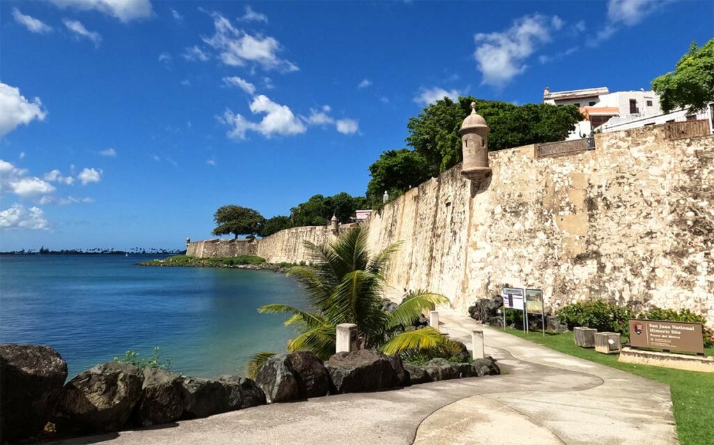 best cheap island vacations fort walls large brick wall with walking path along the Caribbean Sea on a sunny day