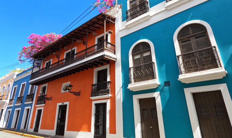 things to do in old San Juan - pic of multicolored buildings green ,teal, blue with balconies and flowers on a sunny day