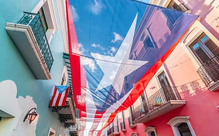 top things to do in San Juan PR - finding Puerto Rico flags this one hanging above the road with colorful buildings on either side
