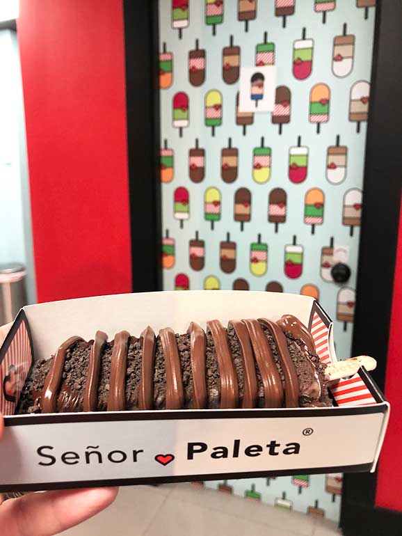 chocolate covered popsicle on a tray with señor paleta and popsicles in the background