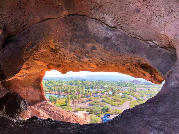 view from inside rock hole looking at palm trees and parking lot