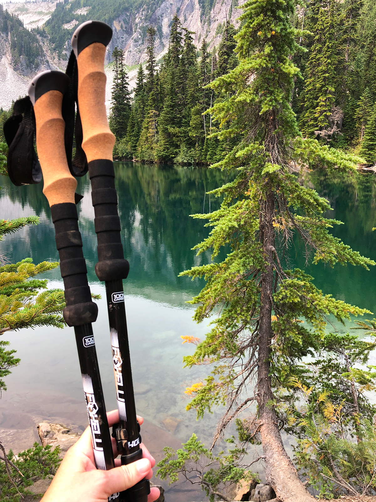 hiking poles close up with teal lake in background