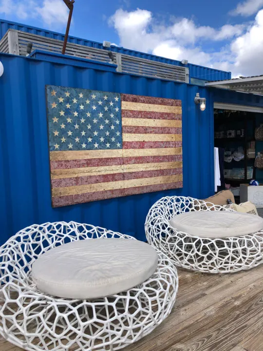 blue wall with large American flag and two white oversized lounge chairs