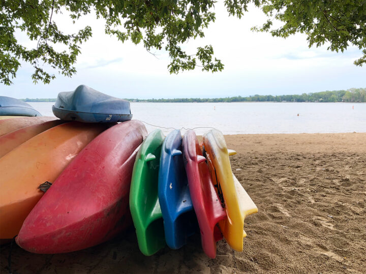multiple colored kayaks on Kelleys island state park beach with sand and lake