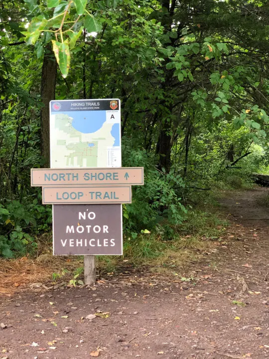 sign at forested trail entrance that includes map and north shore loop trail no motor vehicles