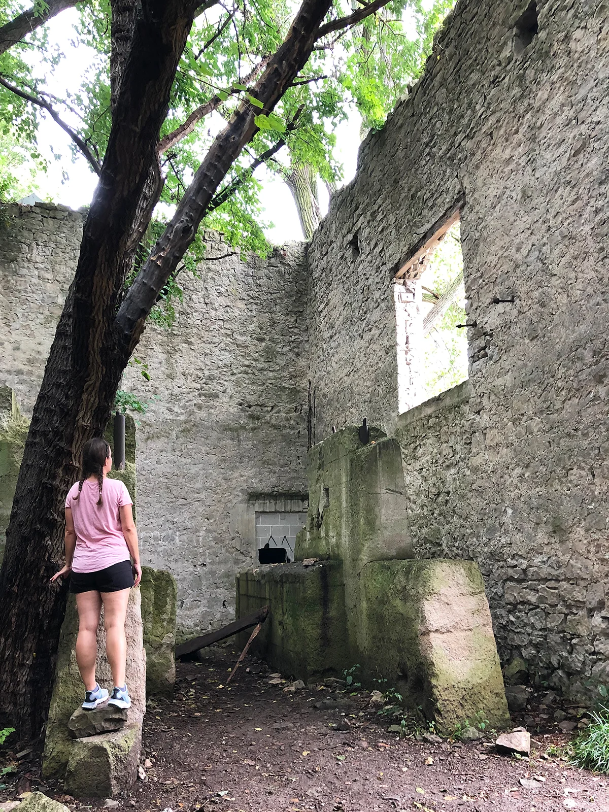 things to do on Kelleys island standing near tree in old ruins woman with pink shirt black shorts