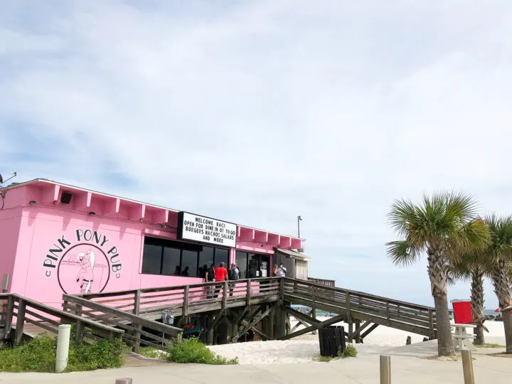 photo of pink pony pub deck with pink building and palm trees on the beach